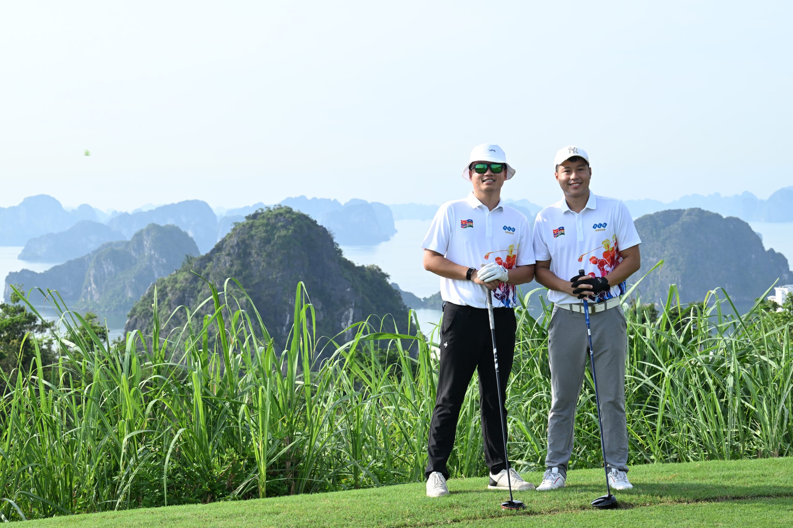 Hai golfer trẻ chụp hình lưu niệm với phông nền vịnh Hạ Long tại giải golf FLC WAGC Vietnam 2025.
