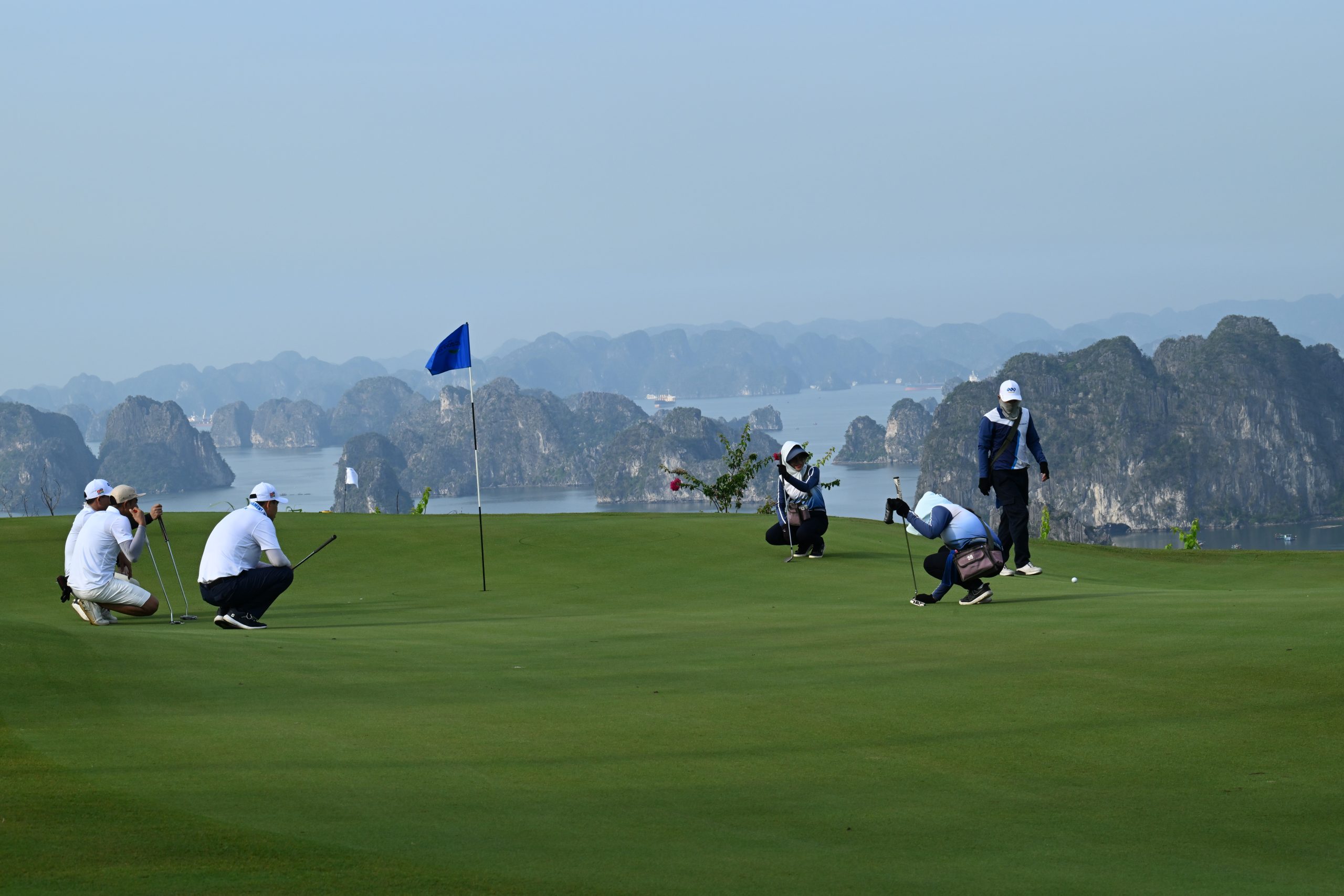 Các golfer thực hiện cú putting tại green, phía sau là khung cảnh vịnh Hạ Long hùng vĩ trong khuôn khổ giải golf FLC WAGC Vietnam 2025.